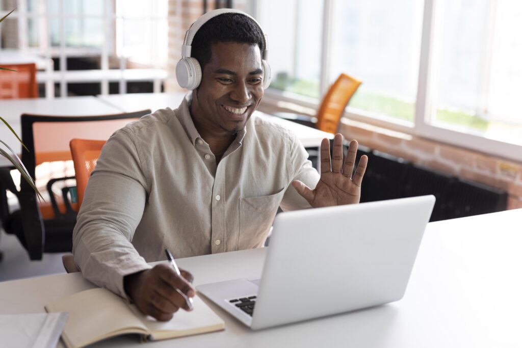 Student waving to his teacher from behind his laptop, ready to start his online Dutch conversation lesson.
