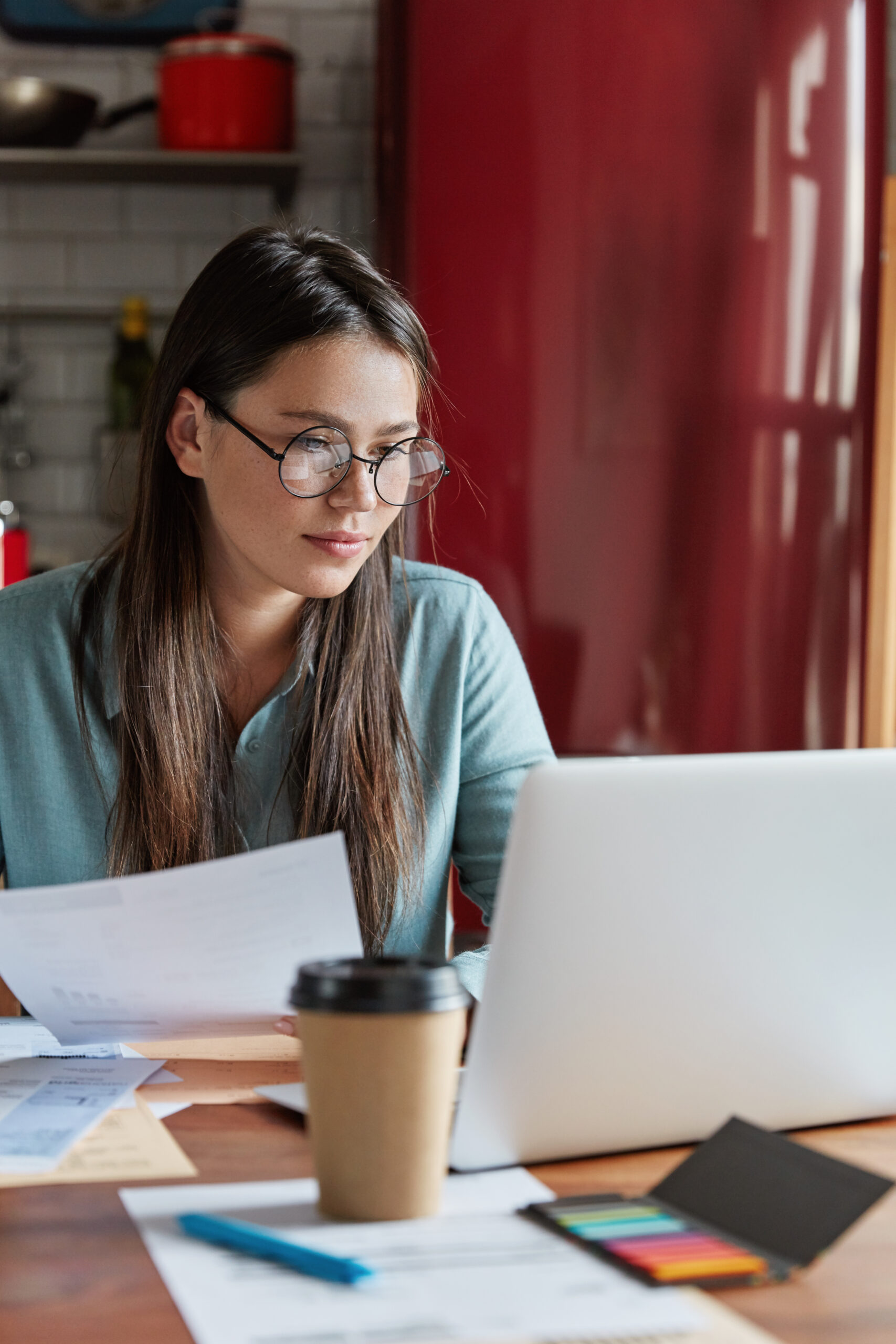 Girl with glasses behind her laptop, following a Dutch B1 exam course.