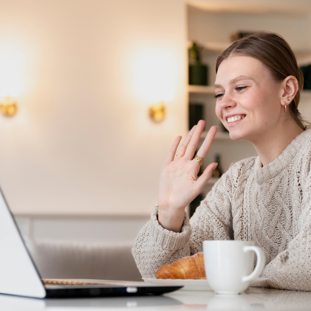 Young woman with her laptop in a brightly lit room, with a cup of coffee on the table.