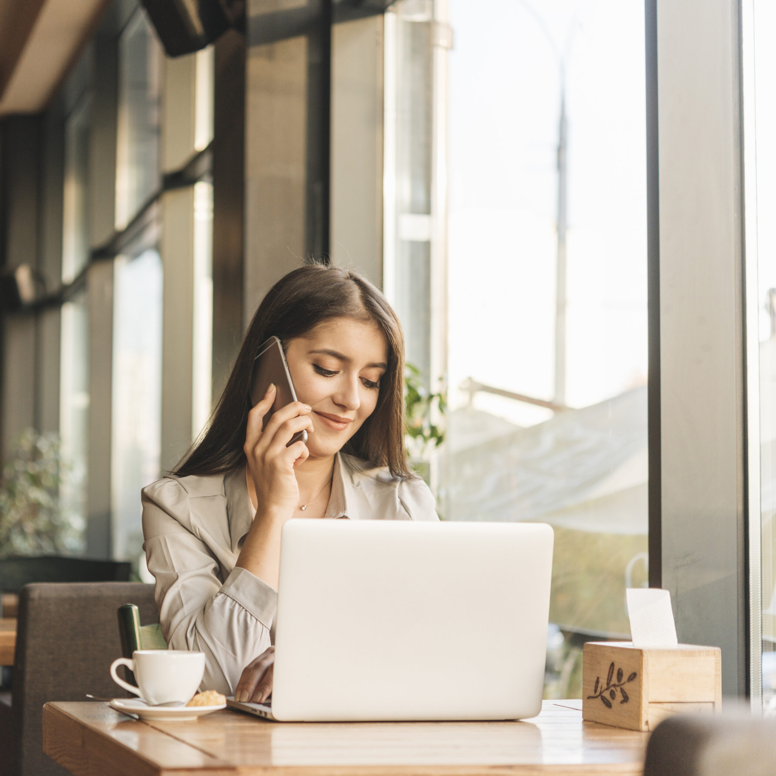 Young woman with a laptop, having a phone conversation on Dutch lessons.