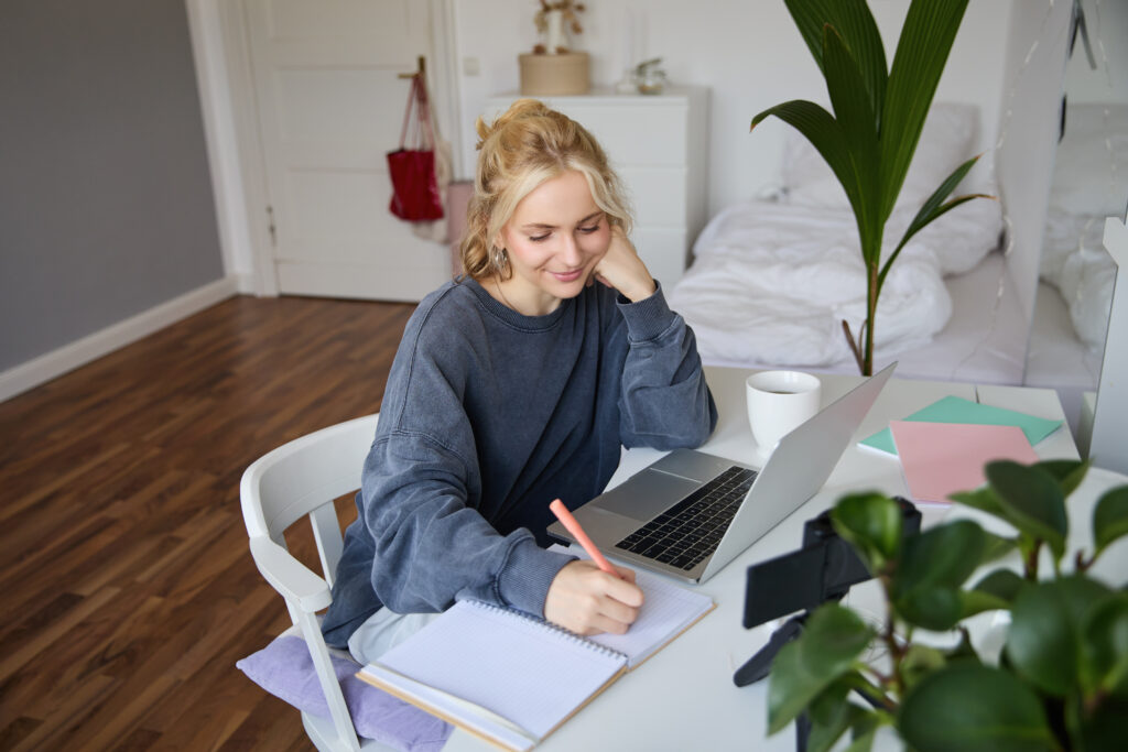 Young woman writing notes in her notebook as she prepares for her Dutch exam.
