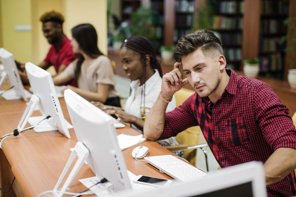 Students sitting in a row, each behind a desktop screen.