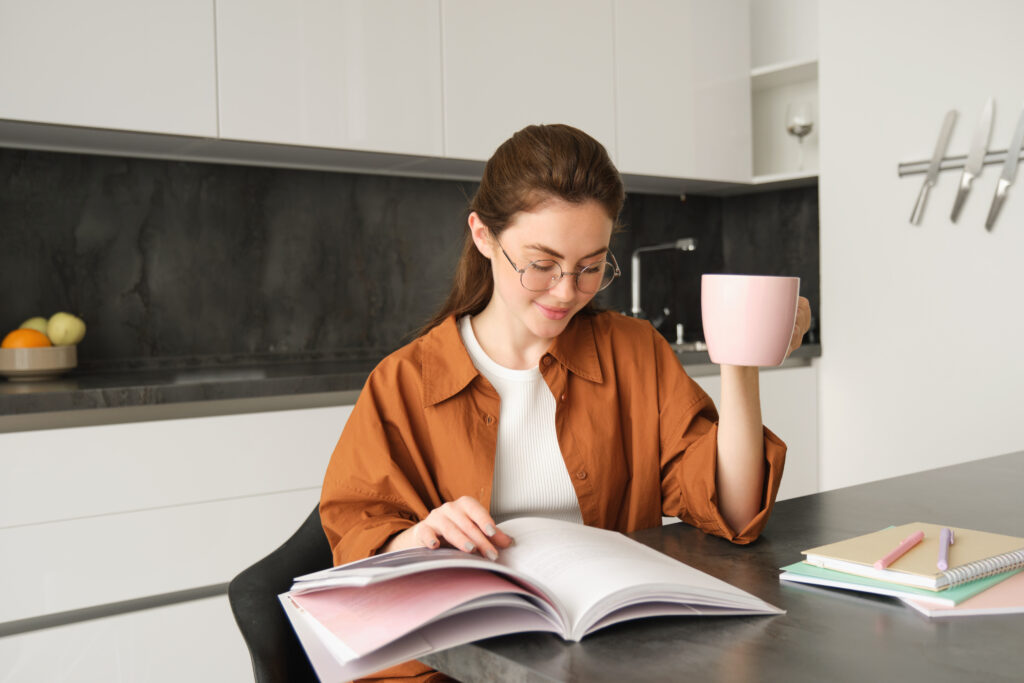 Female student going through her Dutch grammar book while enjoying a cup of coffee.